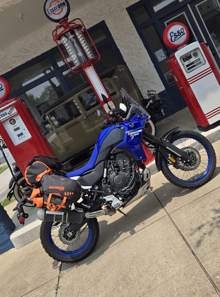 blue motorcycle in front of vintage gas pumps